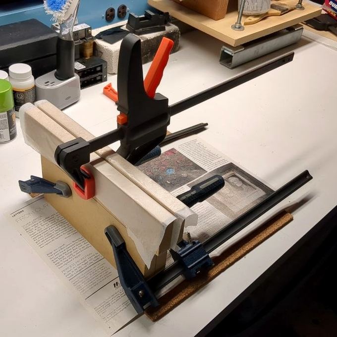 Bar clamps applying even pressure to a text block in a home workbench press